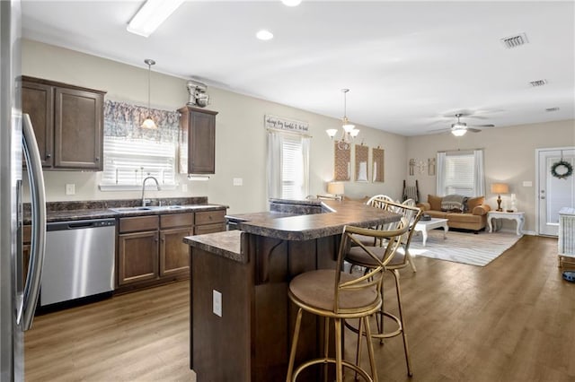 kitchen featuring sink, decorative light fixtures, appliances with stainless steel finishes, a kitchen breakfast bar, and a kitchen island