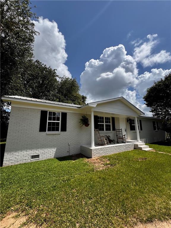 17080A Wayne Johnson Ln, Fairhope, AL 36532 - view of front facade with brick siding, a front yard, a porch, crawl space, and metal roof