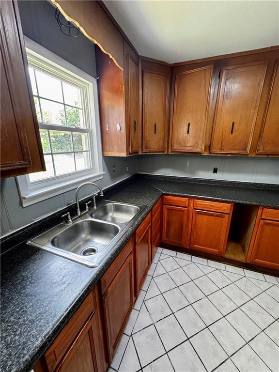 17080A Wayne Johnson Ln, Fairhope, AL 36532 - kitchen with a sink, light tile patterned floors, brown cabinetry, and dark countertops