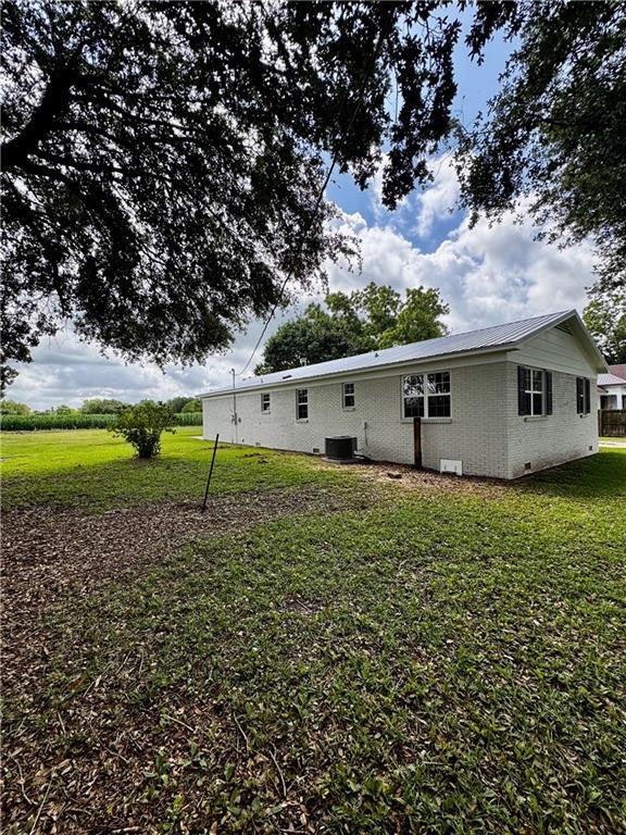 17080A Wayne Johnson Ln, Fairhope, AL 36532 - back of house featuring cooling unit, a lawn, brick siding, and metal roof