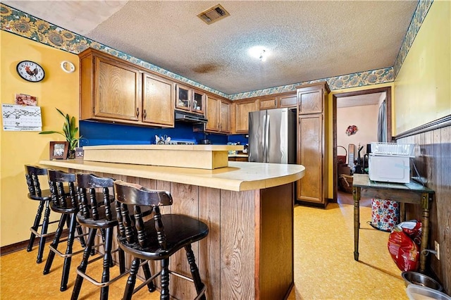 8170 Wilmer Georgetown Rd, Wilmer, AL 36587 - kitchen with a kitchen breakfast bar, a peninsula, a textured ceiling, freestanding refrigerator, and under cabinet range hood