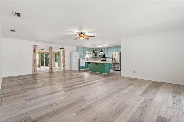 unfurnished living room with baseboards, a ceiling fan, visible vents, and light wood-style floors