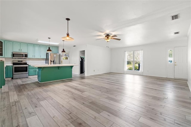 kitchen with appliances with stainless steel finishes, light countertops, green cabinets, and a kitchen bar