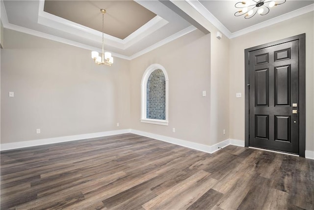 foyer entrance featuring an inviting chandelier, a tray ceiling, dark hardwood / wood-style floors, and ornamental molding