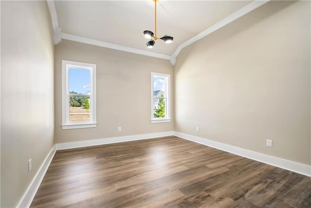 spare room featuring a notable chandelier, dark wood-type flooring, crown molding, and a wealth of natural light