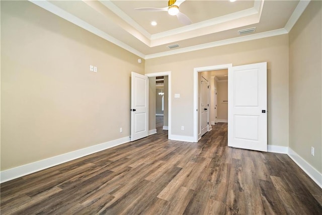 unfurnished bedroom with ceiling fan, a tray ceiling, dark wood-type flooring, and ornamental molding