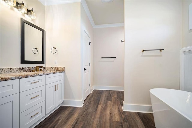 bathroom with vanity, crown molding, wood-type flooring, and a tub to relax in