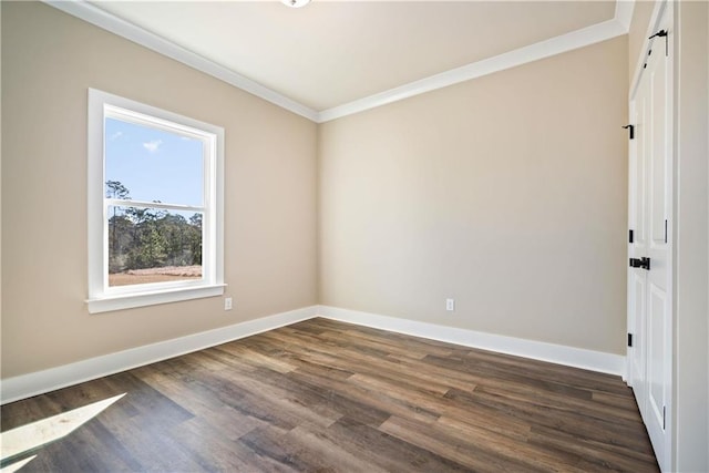 empty room with a barn door, crown molding, and dark wood-type flooring