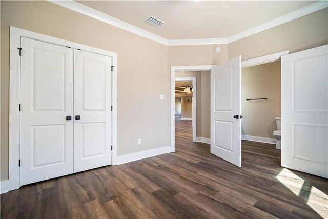 unfurnished bedroom featuring dark hardwood / wood-style flooring, ornamental molding, and a closet