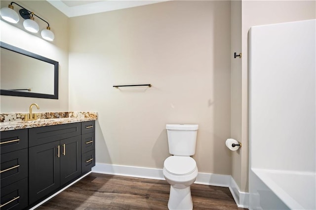 bathroom with toilet, vanity, wood-type flooring, and a bathing tub