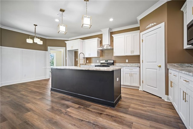 kitchen with appliances with stainless steel finishes, wall chimney range hood, white cabinets, and decorative light fixtures