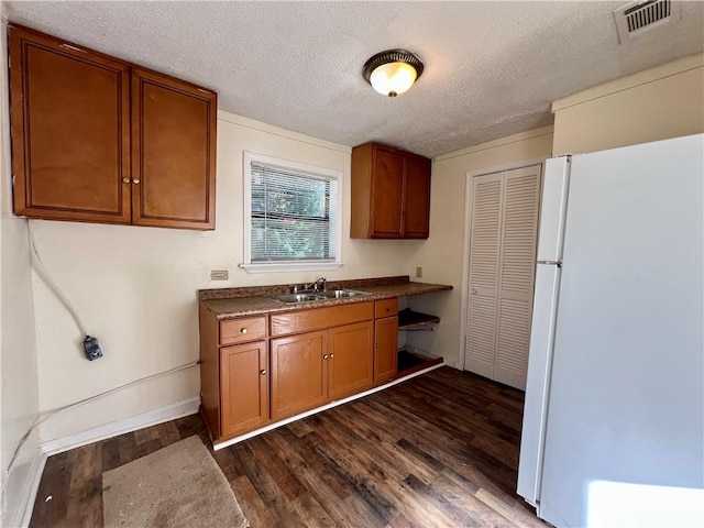 kitchen featuring sink, dark hardwood / wood-style floors, a textured ceiling, and white refrigerator