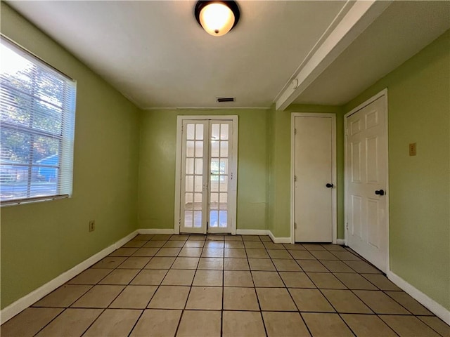 tiled spare room featuring french doors