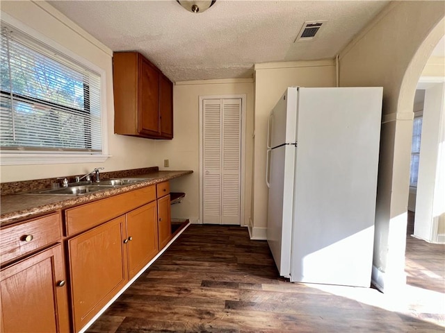 kitchen featuring a textured ceiling, sink, dark wood-type flooring, and white refrigerator