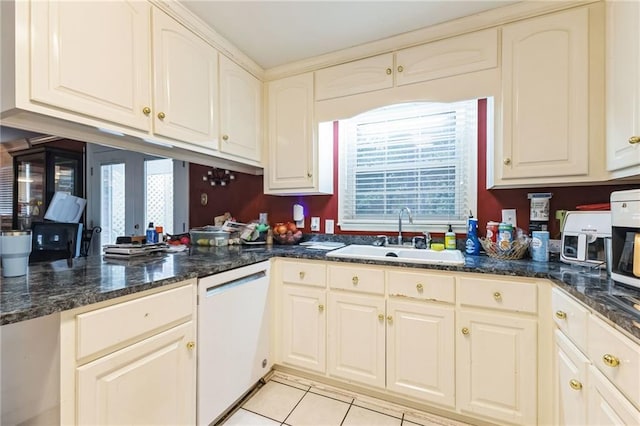 kitchen with light tile patterned flooring, dark stone countertops, dishwasher, and a sink