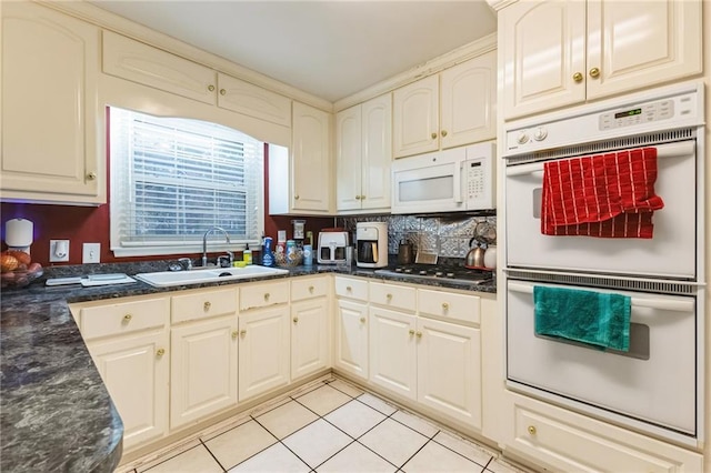 kitchen with white appliances, light tile patterned floors, tasteful backsplash, and a sink