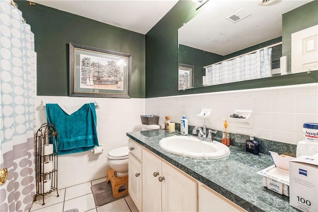 full bath with vanity, tile patterned flooring, wainscoting, tile walls, and toilet