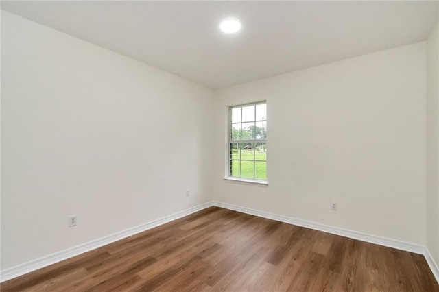 spare room with dark wood-style flooring and baseboards
