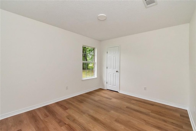 unfurnished room featuring light wood-type flooring, baseboards, and visible vents