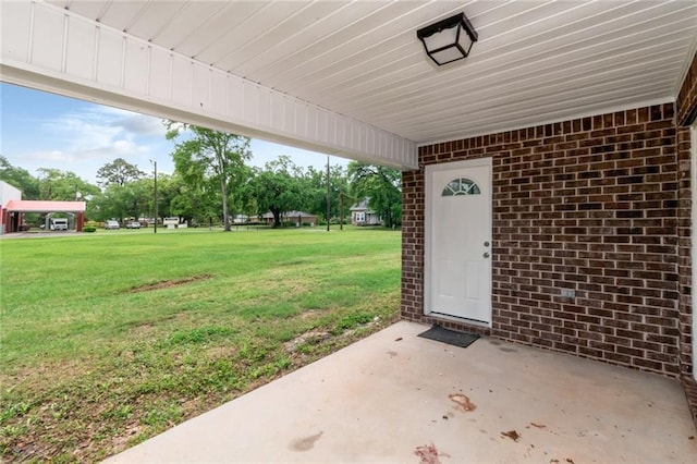 property entrance with a yard, brick siding, and a patio area