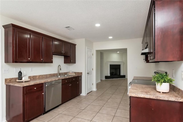 kitchen with light tile patterned floors, a fireplace with raised hearth, visible vents, dishwasher, and a sink