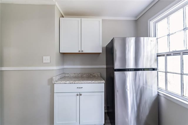 kitchen featuring white cabinets, stainless steel fridge, and plenty of natural light