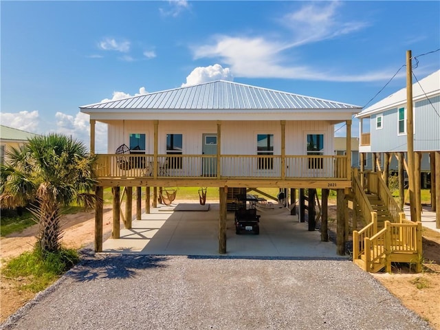 exterior space featuring metal roof, a carport, gravel driveway, and stairs