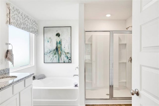 bathroom featuring hardwood / wood-style flooring, vanity, and plus walk in shower