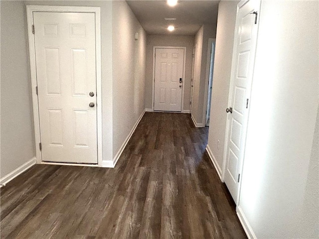 hall featuring baseboards and dark wood-type flooring