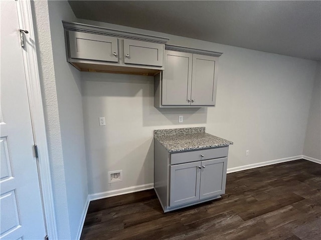 kitchen with gray cabinets, stone counters, and dark wood-type flooring