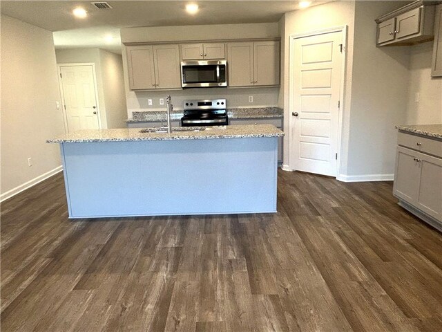 kitchen featuring sink, a kitchen island with sink, appliances with stainless steel finishes, and dark wood-type flooring