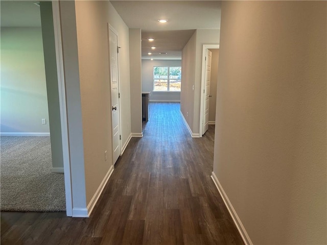 hall with dark wood-style flooring and baseboards