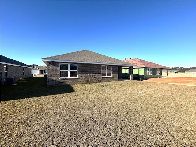 back of property featuring a yard and central AC