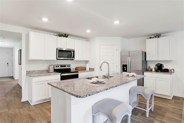 kitchen with sink, white cabinetry, stainless steel appliances, and an island with sink