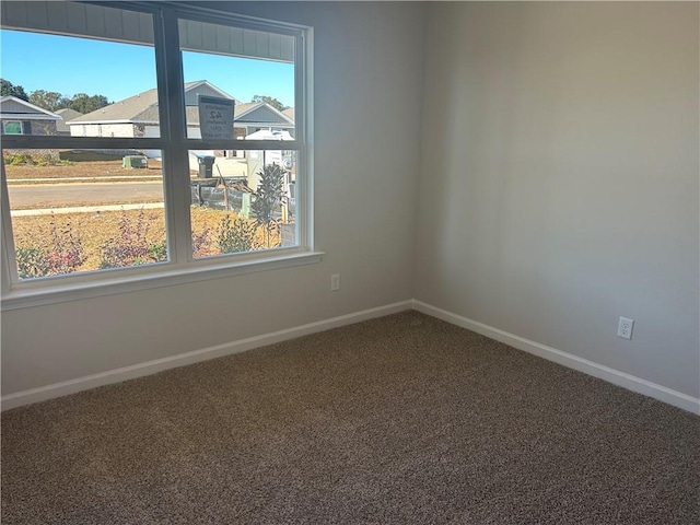 carpeted empty room featuring baseboards