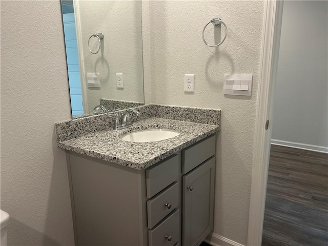 bathroom with wood finished floors, vanity, and baseboards