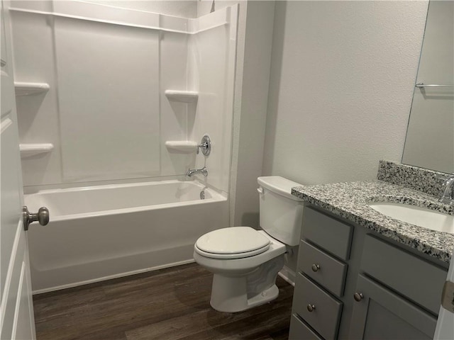 bathroom with shower / tub combination, a textured wall, toilet, wood finished floors, and vanity