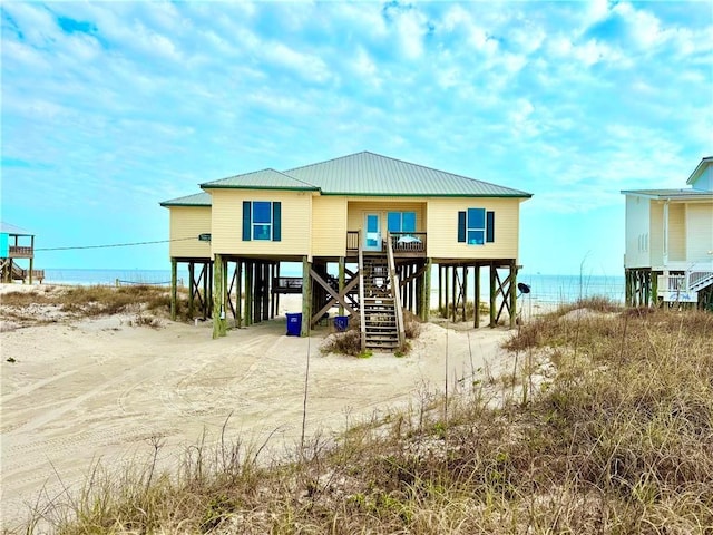 rear view of property with a carport, driveway, metal roof, and a water view