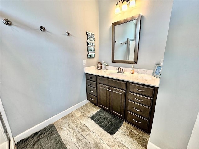 bathroom with vanity, baseboards, and wood finish floors