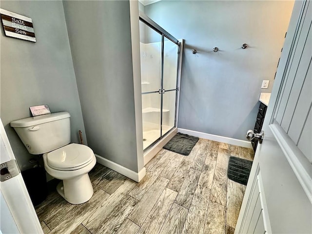 bathroom featuring baseboards, toilet, a stall shower, and wood tiled floor