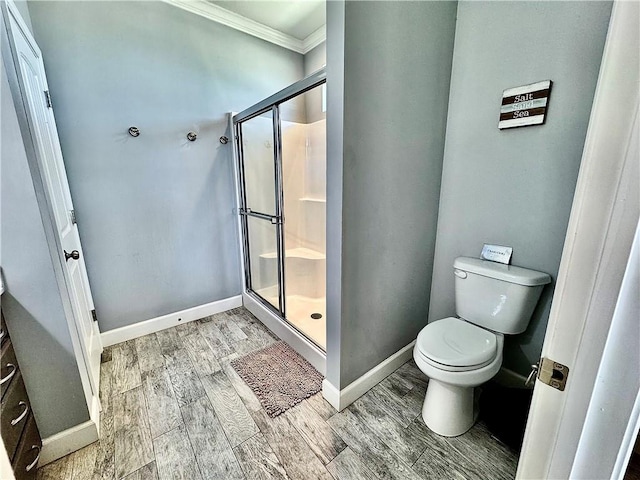 bathroom with toilet, a stall shower, ornamental molding, wood finished floors, and baseboards