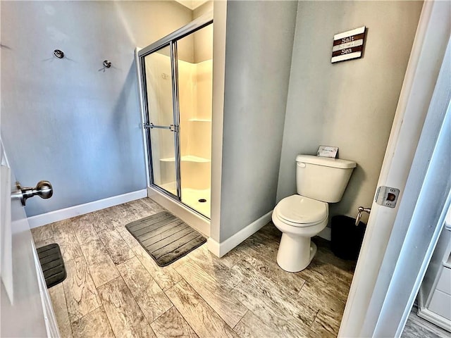 bathroom featuring a shower stall, toilet, baseboards, and wood tiled floor