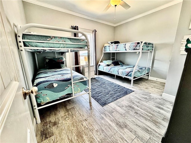 bedroom with a ceiling fan, wood finished floors, baseboards, and ornamental molding