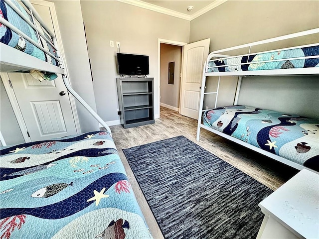 bedroom with electric panel, baseboards, wood finished floors, and ornamental molding