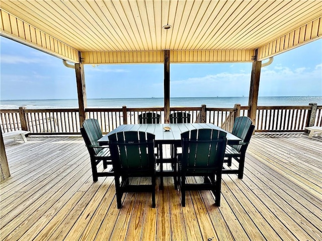 wooden terrace with outdoor dining area and a water view