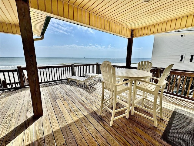 wooden terrace with outdoor dining area and a water view