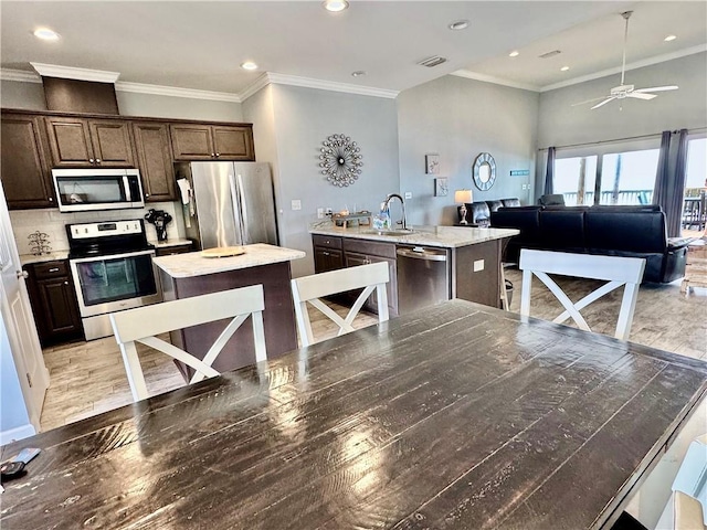 kitchen with visible vents, a kitchen island, a sink, dark brown cabinetry, and appliances with stainless steel finishes