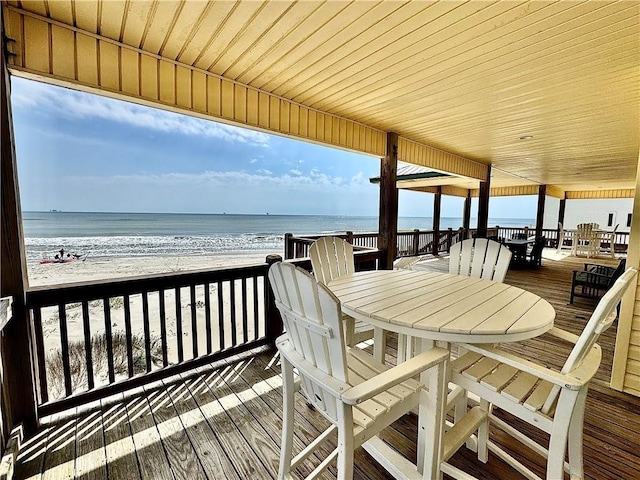 exterior space with outdoor dining space, a view of the beach, and a deck with water view