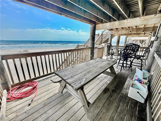 deck featuring stairway, a beach view, and a water view