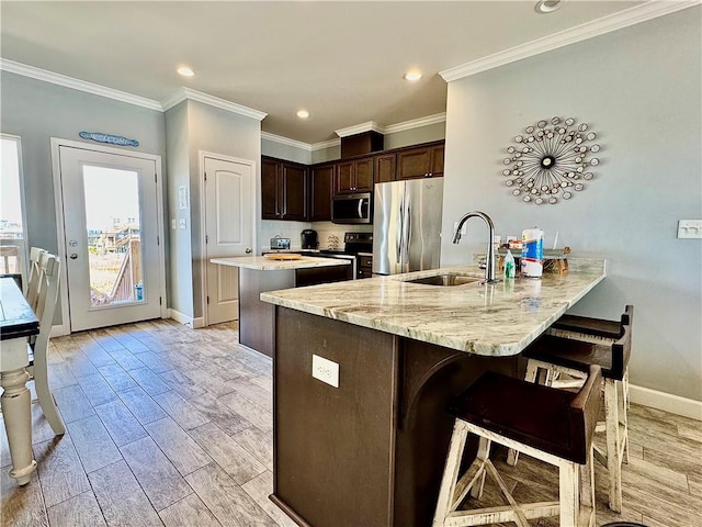 kitchen featuring a sink, stainless steel appliances, a peninsula, light wood finished floors, and dark brown cabinets